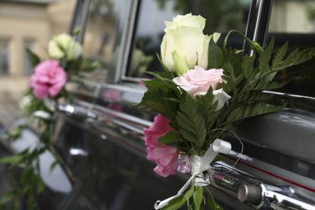 Blumenarrangements in Weiß und Rosa an einer Autotür für eine Hochzeit.