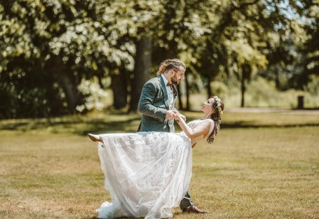 Paar tanzt in einem Park, Braut in weißem Kleid, Bräutigam in Anzug.