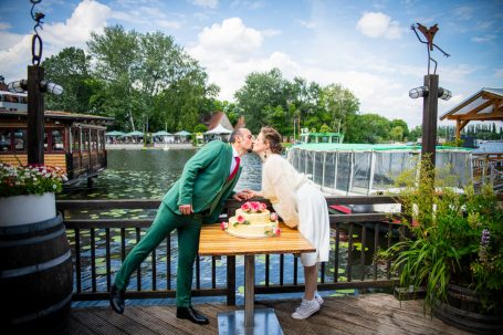 Paar küsst sich romantisch vor einer malerischen Kulisse am Wasser.